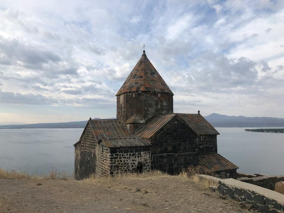 An old church on a hill overlooking a body of water