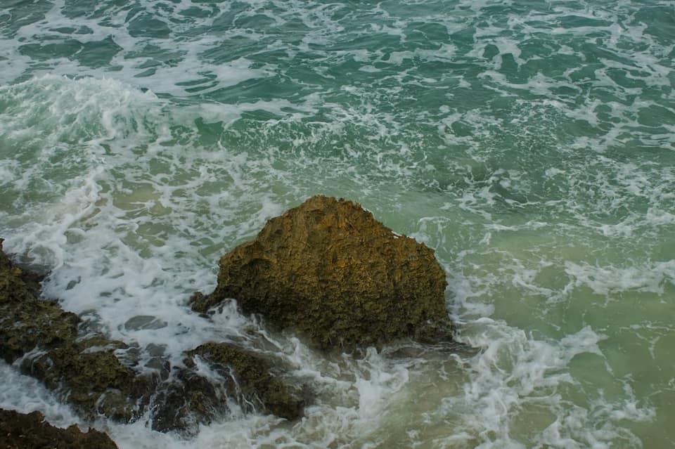 Waves crash against a large rock in the ocean