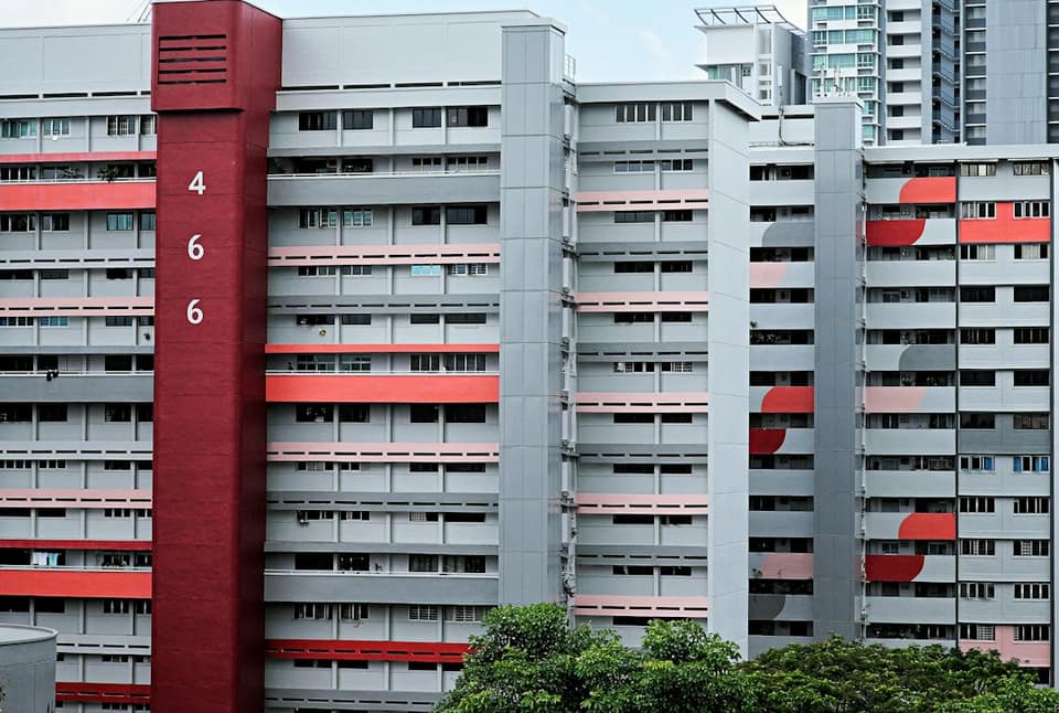 A tall red and grey building next to trees