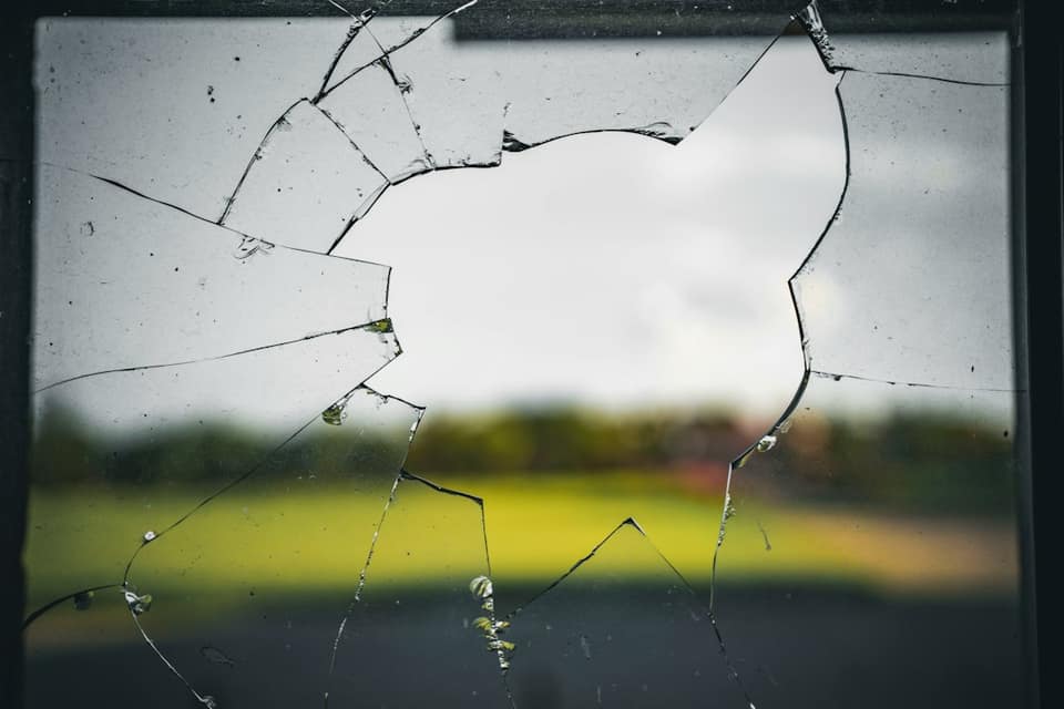 A broken glass window with a field in the background