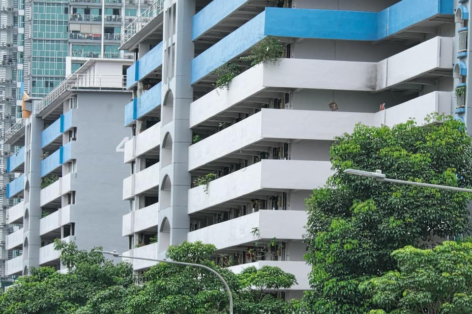 A tall building with many balconies and trees in front of it