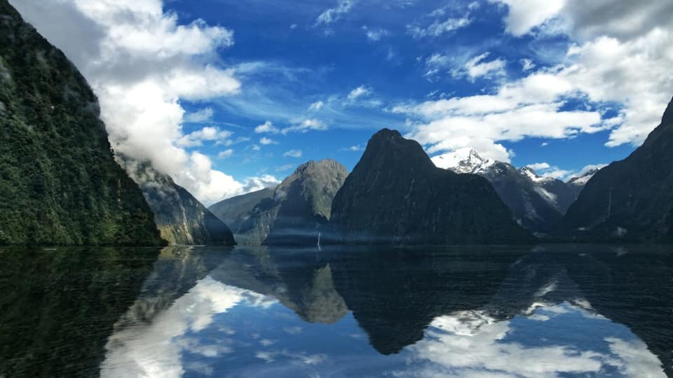 Lake near mountain under blue sky and white clouds during daytime