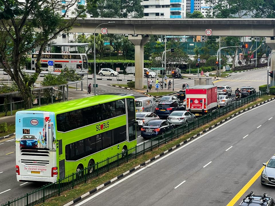 A green double decker bus driving down a highway