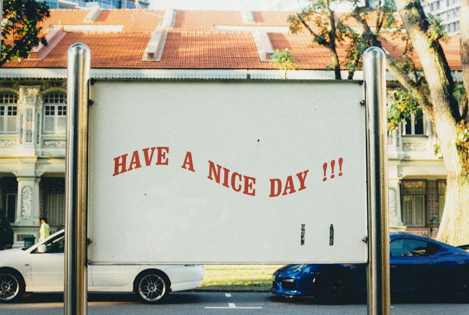 White and blue vehicles on road and have a nice day text on post